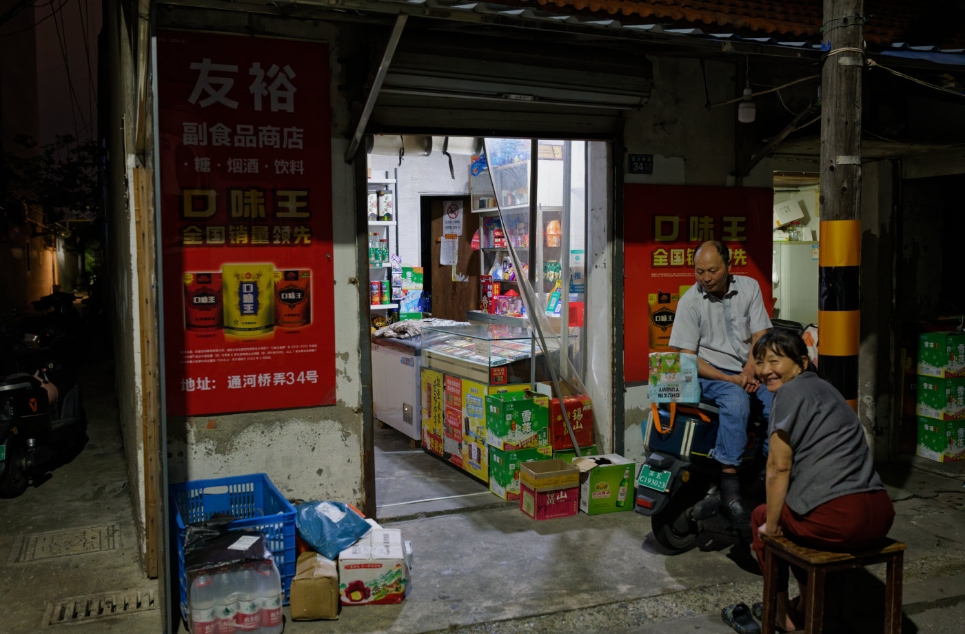 小巷里的烟酒店门口，两个人正在拉家常。看到我拍照，女人笑着回头看我。