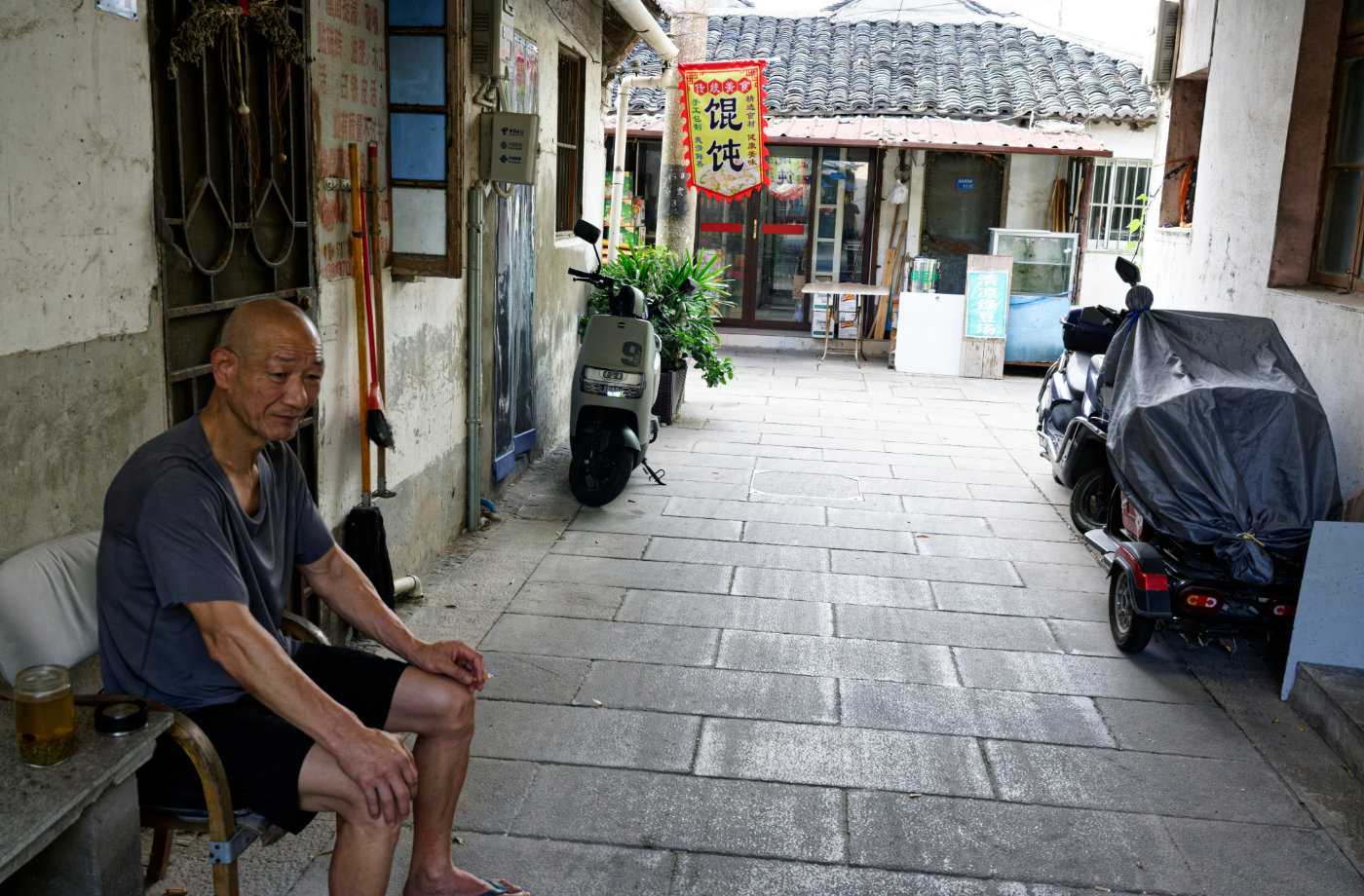 巷子尽头有人来往，门口坐着的老人安静地看着街面。