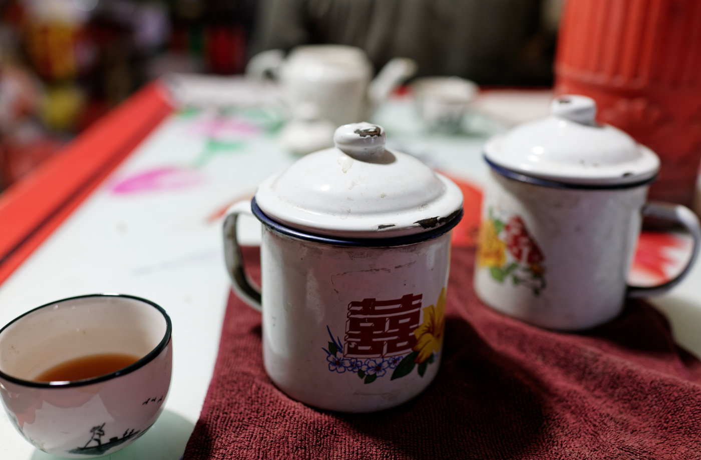 花纹搪瓷缸、茶杯和桌布上的旧图案，组成一组属于老茶馆的简单静物。