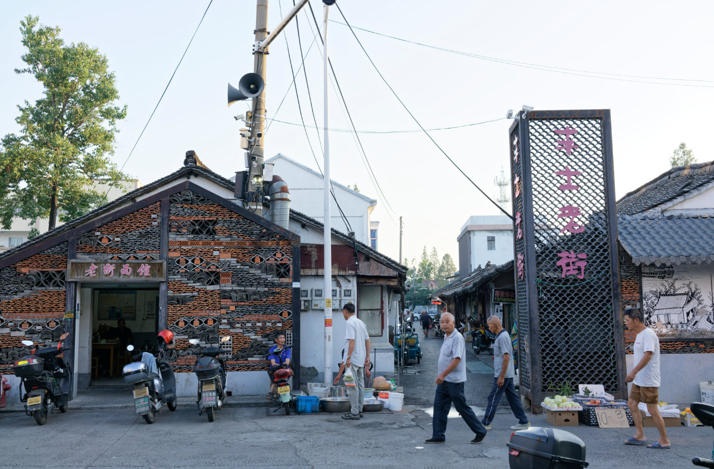 丰士老街入口旁的老桥面馆、街口摊位和来往的老人,把这里的日常一下子带到眼前。