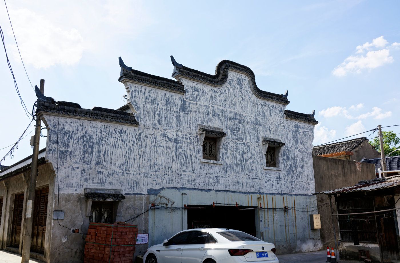 一栋仍保留旧轮廓的民居,门窗、墙面和停在下面的汽车把不同年代叠在了一起。
