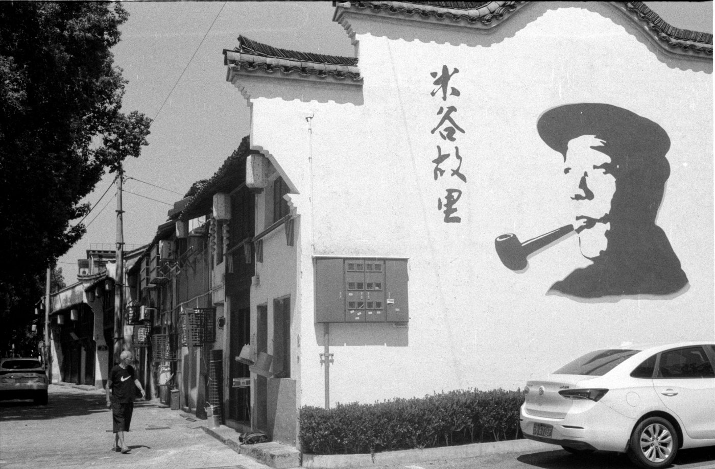 老街墙上的米谷主题宣传画,行人从一旁经过。